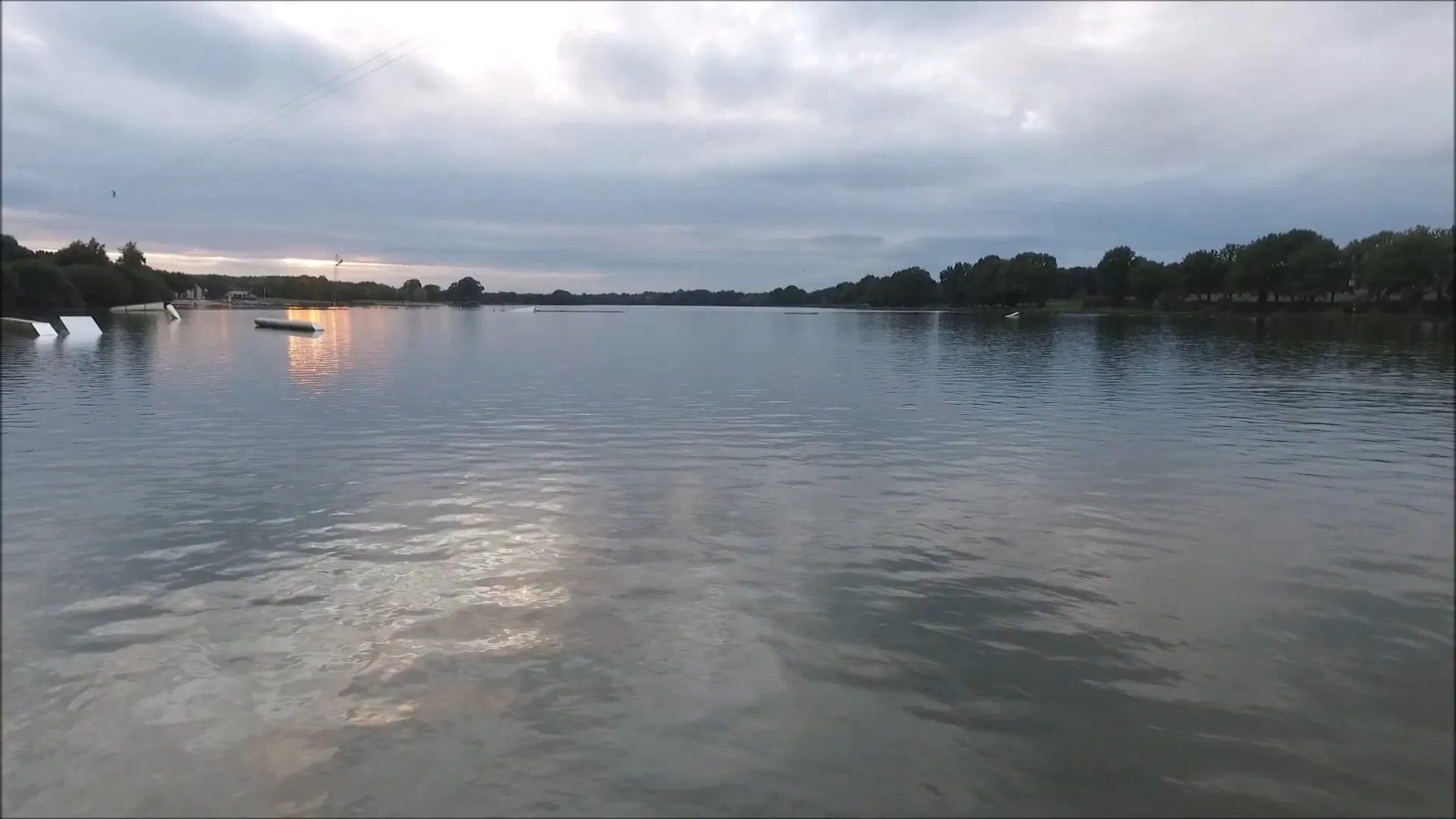 Plan d'eau de la base de loisirs de La Rincerie en Mayenne, montrant une étendue d'eau calme propice aux loisirs nautiques et à la baignade en milieu rural