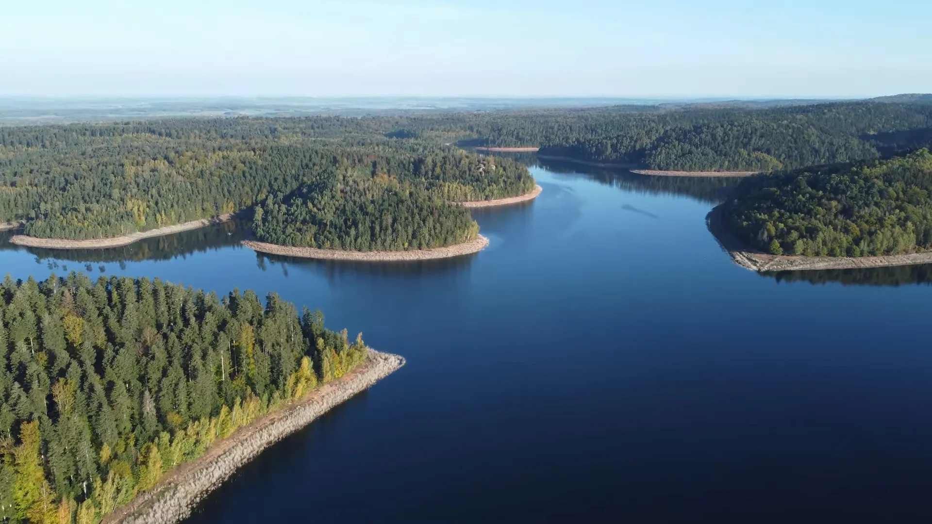 Les rives sauvages et boisées du Lac de Pierre-Percée, évoquant les paysages canadiens avec ses contours découpés et sa forêt dense de sapins