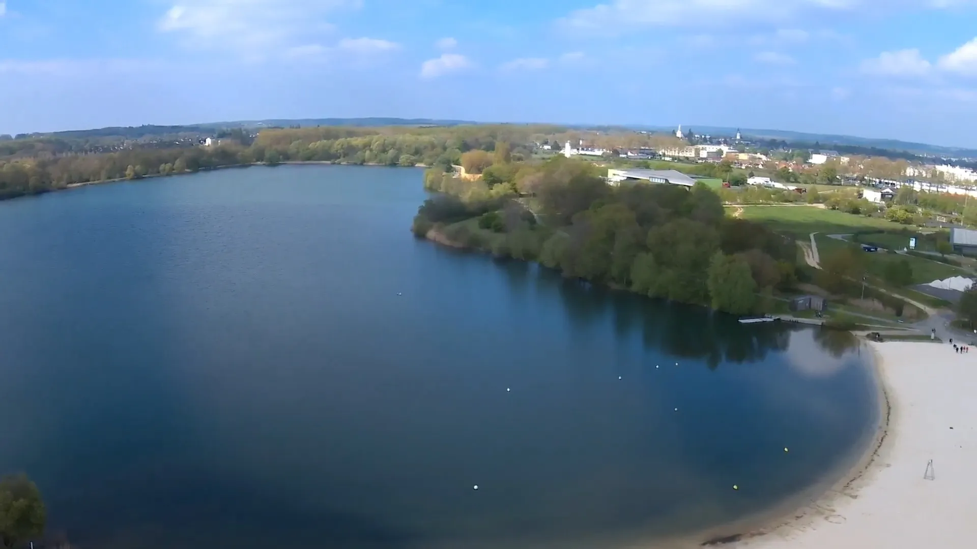Bord du Lac de la Monnerie à La Flèche, dévoilant une eau claire et des berges aménagées avec plage de sable pour la baignade estivale