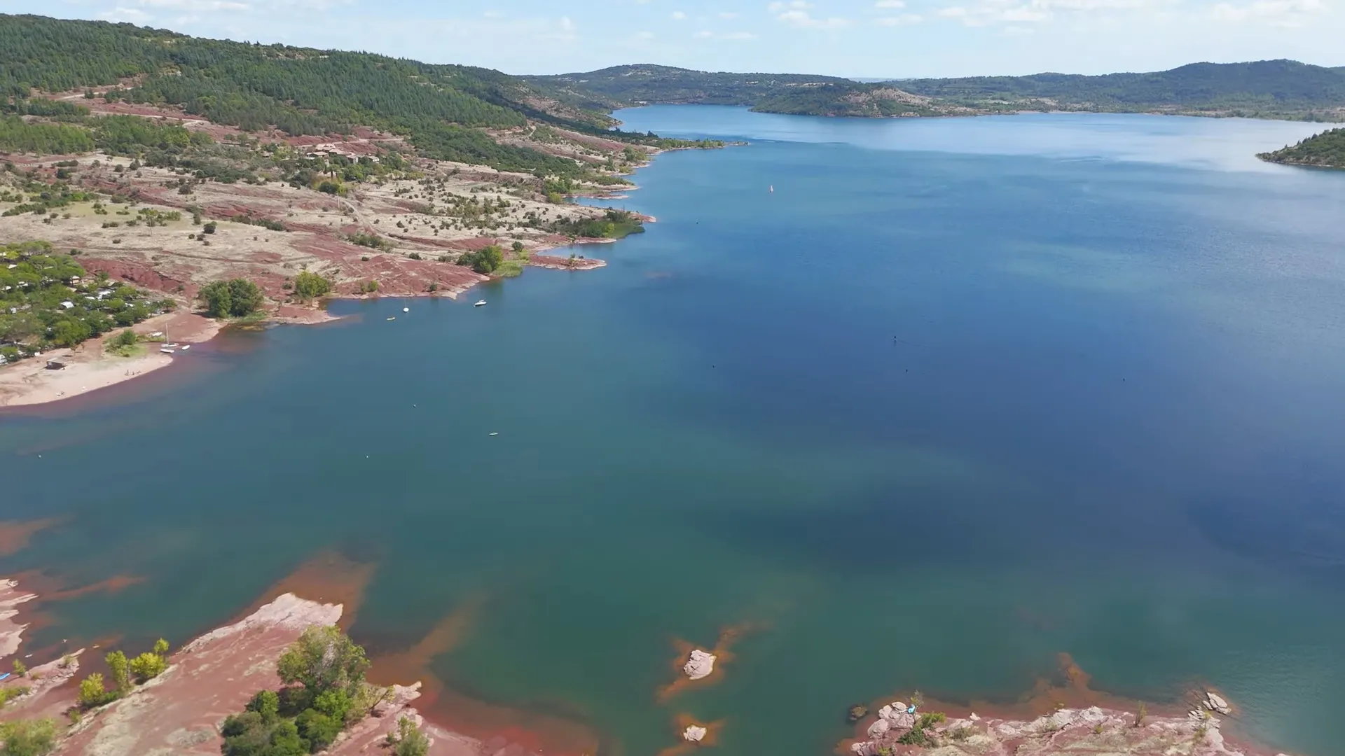 Vue aérienne par drone montrant l'immensité du lac du Salagou, ses presqu'îles rouges et la garrigue environnante