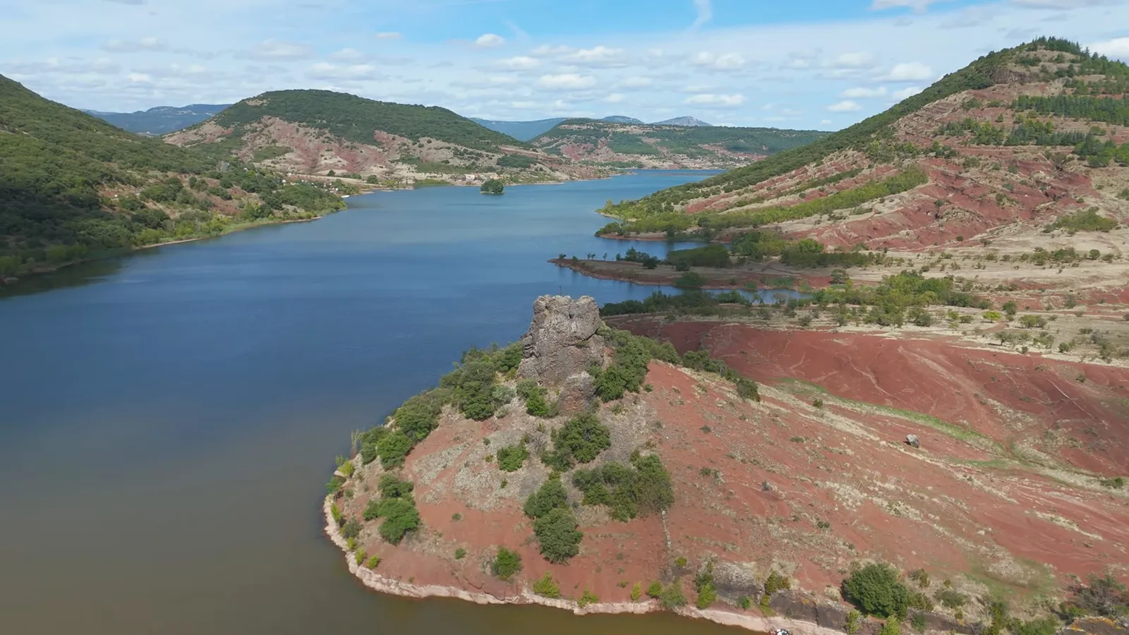 Contraste saisissant entre la surface bleue de la retenue d'eau du Salagou et la colline de terre rouge