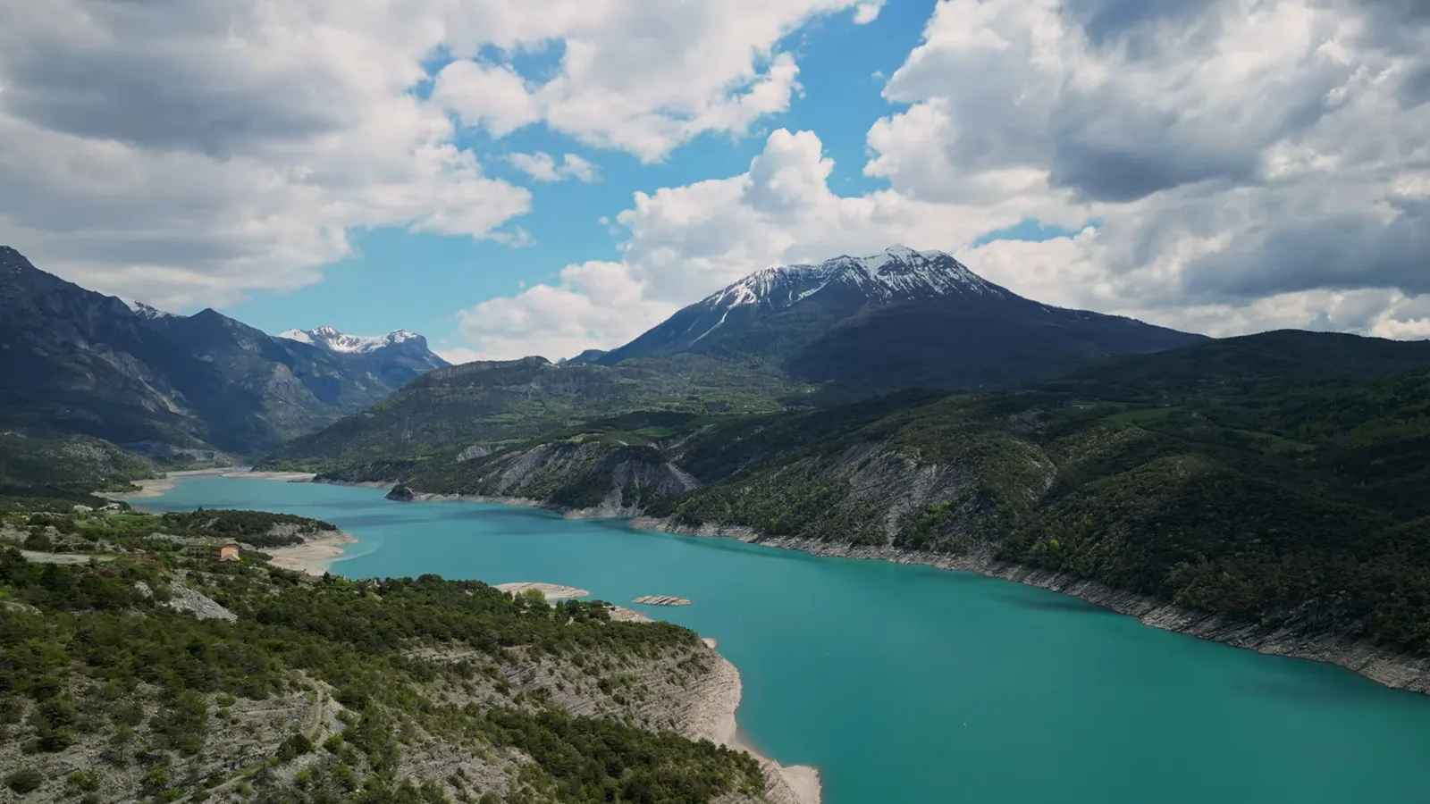 Lac de Serre-Ponçon par basses eaux face aux montagnes aux sommets enneigés